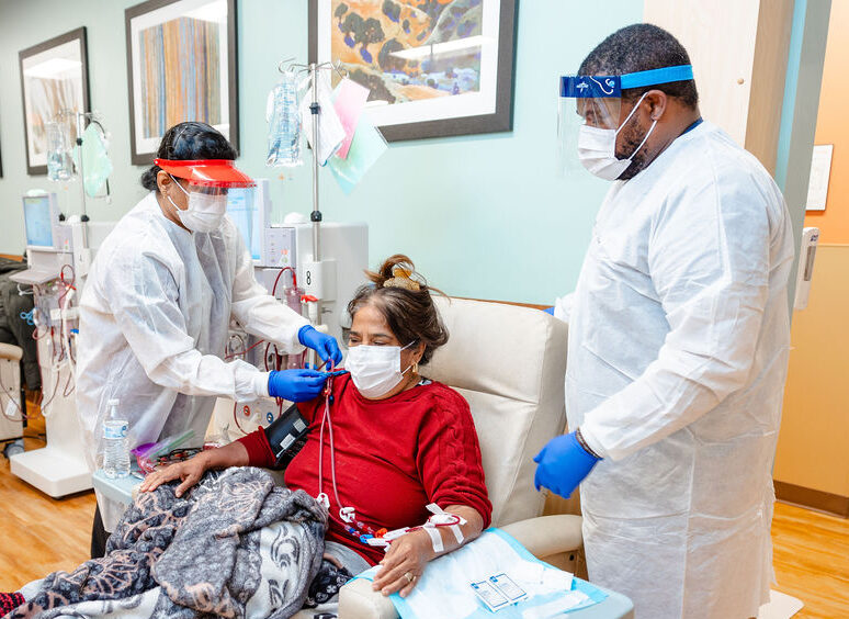 Doctors with female patient in chair.