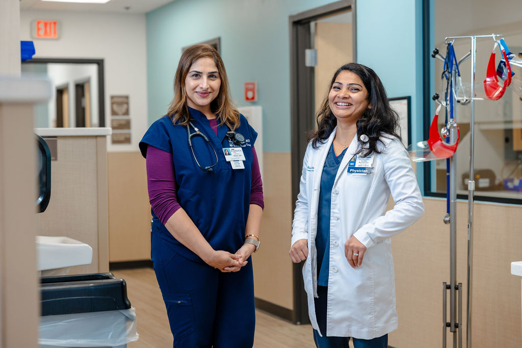 Doctor and nurse standing in clinic hallway.